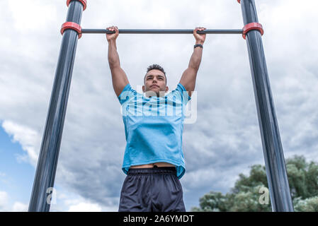 Sport Mann zieht sich auf der horizontalen Leiste, Ausbildung in der Stadt während der Sommermonate, einen aktiven Lebensstil, moderne Fitness-training. Stockfoto
