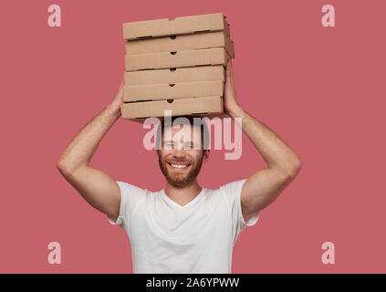Kurier hält viele Pizzakartons auf Wand isoliert Stockfoto