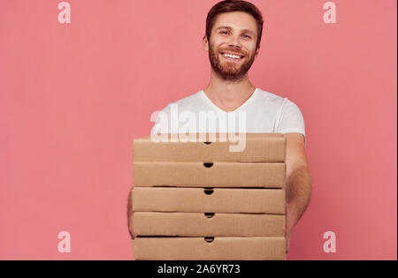 Kurier hält viele Pizzakartons auf Wand isoliert Stockfoto