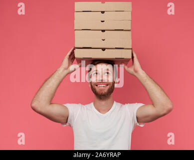 Kurier hält viele Pizzakartons auf Wand isoliert Stockfoto