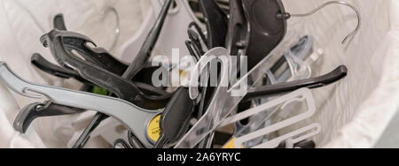 Einstellen der Gehänge in einem Korb gestapelt Kleidung in einem Wandschrank oder in der Anzeige zu hängen Stockfoto