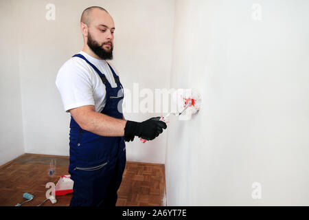 Bauarbeiter tun beenden Renovierung im Apartment. Professionelle Maler Auftragnehmer mit weißer Farbe bürstenrolle Gemälde an der Wand. Stockfoto