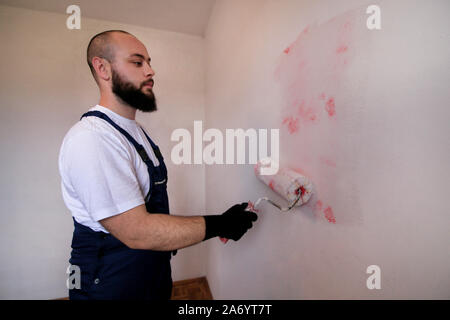 Bauarbeiter tun beenden Renovierung im Apartment. Professionelle Maler Auftragnehmer mit weißer Farbe bürstenrolle Gemälde an der Wand. Stockfoto