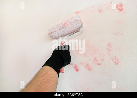 Bauarbeiter tun beenden Renovierung im Apartment. Professionelle Maler Auftragnehmer mit weißer Farbe bürstenrolle Gemälde an der Wand. Stockfoto