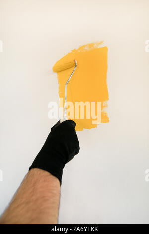 Bauarbeiter und Handwerker tun beenden Renovierung im Apartment. Maler mit paint Bürstenrolle Anstrich der Wand mit der Farbe gelb. Stockfoto