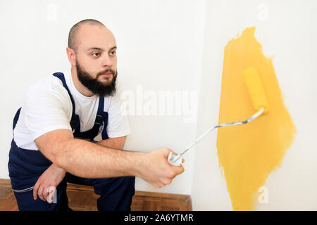 Bauarbeiter und Handwerker tun beenden Renovierung im Apartment. Maler mit paint Bürstenrolle Anstrich der Wand mit der Farbe gelb. Stockfoto