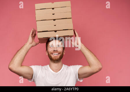 Kurier hält viele Pizzakartons auf Wand isoliert Stockfoto