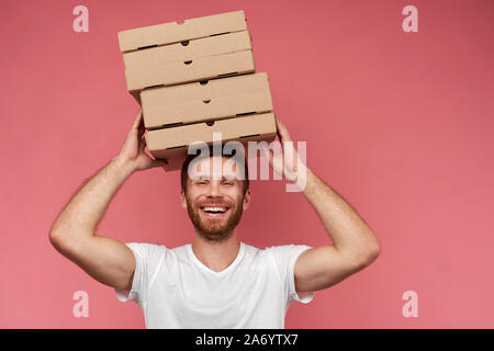 Kurier hält viele Pizzakartons auf Wand isoliert Stockfoto