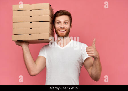 Kurier hält viele Pizzakartons auf Wand isoliert Stockfoto