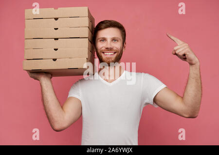 Kurier hält viele Pizzakartons auf Wand isoliert Stockfoto