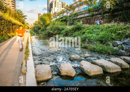 Seoul Korea, 23. September 2019: Menschen zu Fuß entlang Cheonggyecheon Strom bei Sonnenuntergang mit dramatischen Licht in Seoul, Südkorea Stockfoto