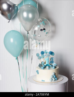 Weiß und Blau Kuchen mit Süßigkeiten und Cookie Nummer eins auf junge ersten Geburtstag. Ballons und Konfetti auf Hintergrund Stockfoto