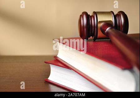 Holz Richter Hammer mit einer Brass Band um den Kopf, die auf der Oberseite von einem geschlossenen roten Gesetz Buch mit flachen Dof und Copyspace Stockfoto
