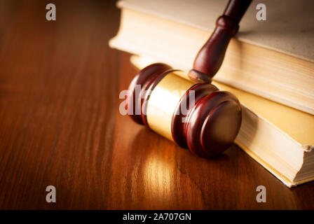 Holz- Hammer in einem Gerichtssaal aufrecht gegen einen Stapel Bücher auf dem Richter Schreibtisch Stockfoto