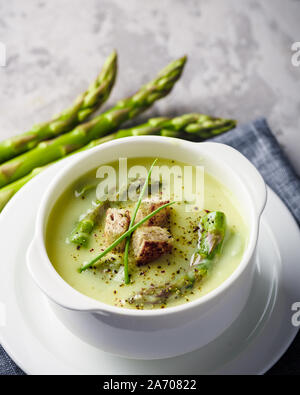 Grüner Spargel Suppe mit Crackern in Weiß Schüssel Nahaufnahme. Essen Fotografie Stockfoto