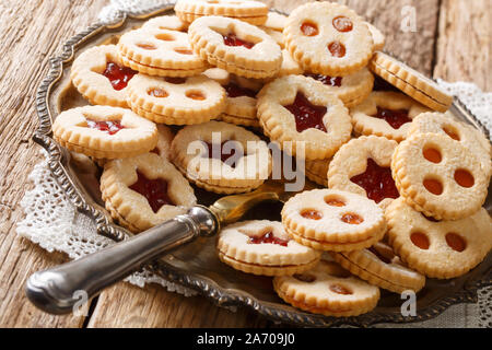 Traditionelle österreichische Weihnachtsplätzchen - Linzer Kekse mit roten Erdbeeren und Aprikosen Konfitüre schließen gefüllt - auf den Tisch. Horizontale Stockfoto