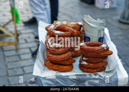 Frittierter Zuckerteig auf dem Straßenstand. Ein paar traditionelle Ringdessert - mit Sirup getränktes Gebäck - auf dem Tablett des Straßenverkäufers Stockfoto