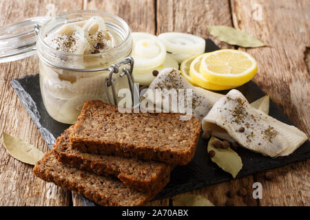 Polnische gesalzene Heringe mit Zwiebeln, Essig, Gewürze in Öl in einem jar Close-up auf dem Tisch. Horizontale Stockfoto