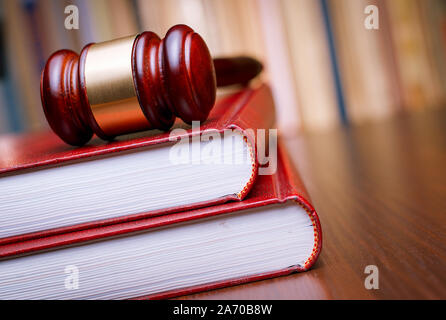 Richter Holz- Hammer ruht auf einem großen roten Gesetz Buch auf einem Tisch in einem konzeptionellen Bild der Justiz und der Polizei Stockfoto
