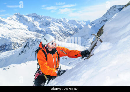 Alpinisten klettern in steilen und schneebedeckte Berge mit einer Axt Stockfoto