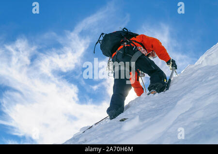 Alpinisten klettern in steilen und schneebedeckte Berge mit einer Axt Stockfoto