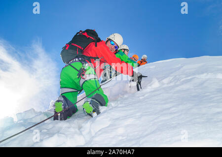 Alpinisten klettern in steilen und schneebedeckte Berge mit einer Axt Stockfoto