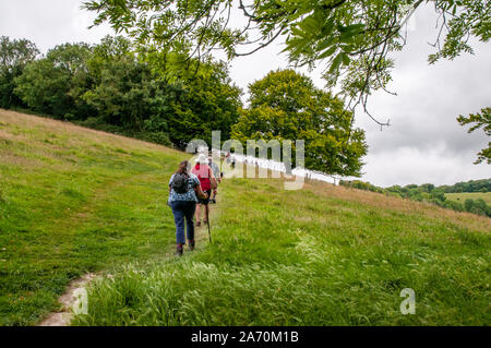 Eine Gruppe von Wanderern zu Fuß auf einem steilen Hügel in der malerischen Landschaft von Hampshire in der Nähe von Beacon Hill National Nature Reserve und Winchester, England. Stockfoto