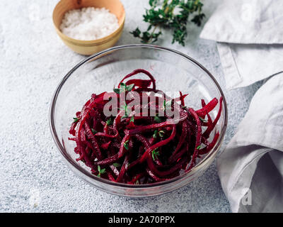 Rohe rote Beete nudeln Salat. Gemüse Nudeln - Spaghetti in Zuckerrüben Glasplatte über Grauzement Hintergrund. Kopieren Sie Platz für Text. Ideen und Rezept für Sauber Essen, Raw vegetarisches Essen Konzept. Stockfoto
