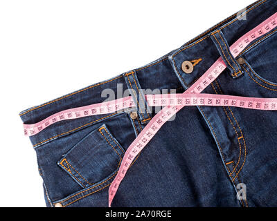 Jeans und rosa Maßband auf weißem Hintergrund. Stockfoto