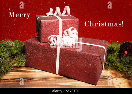 Zwei Weihnachtsgeschenke liegen auf einem Holztisch und eine Grußansage Stockfoto