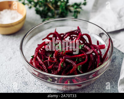 Rohe rote Beete nudeln Salat. Gemüse Nudeln - Spaghetti in Zuckerrüben Glasplatte über Grauzement Hintergrund. Kopieren Sie Platz für Text. Ideen und Rezept für Sauber Essen, Raw vegetarisches Essen Konzept. Stockfoto