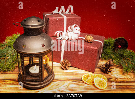 Zwei Weihnachtsgeschenke liegen auf einem Holztisch mit einer Laterne Stockfoto