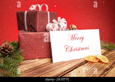 Zwei Weihnachtsgeschenke liegen auf einem Holztisch mit einer Grußkarte Stockfoto