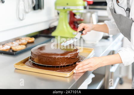 Patissier gießt flüssige Schokolade auf einem Kuchen Stockfoto