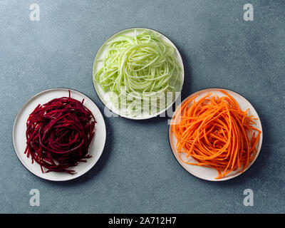 Gemüse Nudeln - Zucchini, Karotten und rote Beete Nudeln auf dem Teller über grauen Stein Hintergrund. Sauber Essen, raw-vegetarisch, essen Konzept. Kopieren Sie Platz für Text. Top View oder flach. Stockfoto