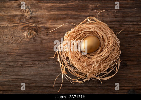 Einzigartige und wertvolle goldene Ei mit Nest auf hölzernen Hintergrund Stockfoto