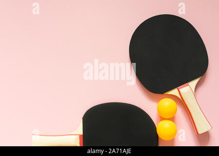 Schwarz Tennis ping pong Schläger und orange Kugeln auf einem rosa Hintergrund isoliert, Sport Ausrüstung für Tischtennis Stockfoto