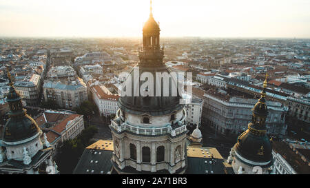 Die aufgehende Sonne scheint durch den Turm der schönen St.-Stephans-Basilika (Szent Istvan Bazilika) bei Sonnenaufgang auf einer Luftaufnahme. Stockfoto