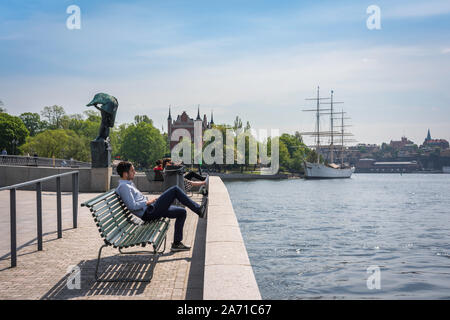 Stockholm Waterfront, Aussicht im Sommer von einem jungen Mann auf einer Bank an der Uferpromenade Blasieholmen in Stockholm, Schweden. Stockfoto