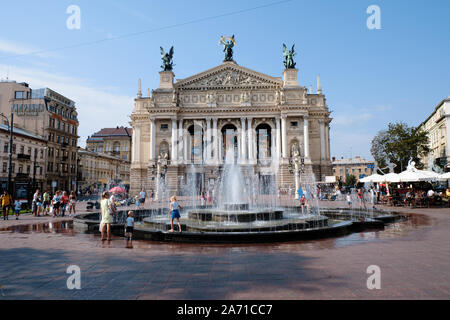 Menschen spielen rund um Brunnen an einem heißen Tag im Vordergrund, auf der Oper im Zentrum von Lviv, Ukraine Stockfoto