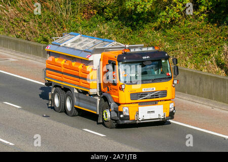 salzstreuer mit einem Fassungsvermögen von 9m3 bei Volvo-Fahrgestellen für die Winterinstandhaltung von Straßen; Fahrzeugführer. Schneepflüge in robuster Ausführung mit geradem Schild auf der Autobahn M61, Großbritannien Stockfoto