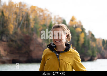 Cute erwachsenes Weibchen tragen ein Tgelb Regenjacke stellt auf einem Boot in der Nähe der Apostel Islands National Lakeshore am Lake Superior in Wisconsin Stockfoto
