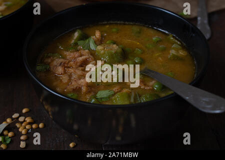 Vegan Linsen, Okra und Erbsen Suppe, garniert mit knackigen Zwiebeln, in schwarz Schalen serviert. Stockfoto