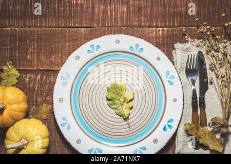 Rustikal gedeckten Tisch für Thanksgiving Dinner mit Herbst Blätter, Eicheln und Kürbisse für die Dekoration. Ansicht von oben mit der Kopie. Stockfoto