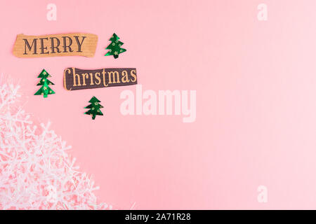 Schneeflocken, Weihnachtsbäume und Frohe Weihnachten Schriftzug Inschrift auf einem rosa Hintergrund. Winterurlaub festliche Begrüßung Geschenkkarte mit Kopie Raum Stockfoto