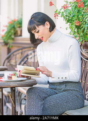 Mädchen trinken Kaffee Buch lesen. Tasse guten Kaffee und angenehmen Buch beste Kombination für perfektes Wochenende. Frau trinken gutes Buch Cafe Terrasse genießen. Selbstverbesserung Konzept. Literatur für Frauen. Stockfoto