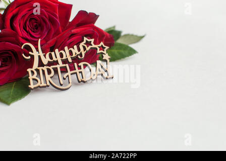 Zusammensetzung der Strauß roter Rosen und dekorative Holz- Gruß auf weißem Hintergrund. Alles Gute zum Geburtstag. Platz für Text. Stockfoto