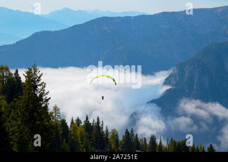 Zwei Personen sind Tandem Paragleiten im Rofangebirge in Richtung nebligen Tal, Österreich Stockfoto