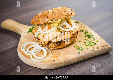 Frische Burger mit Fleisch und Zwiebeln auf Schneidebrett und Holz- Hintergrund Stockfoto