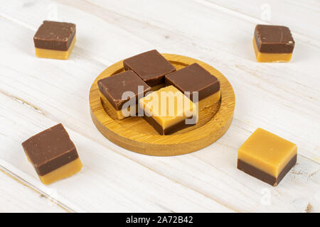 Gruppe der Acht ganze süsse braune Karamell Schokolade Süßigkeiten auf Bambus Untersetzer auf weißem Holz Stockfoto